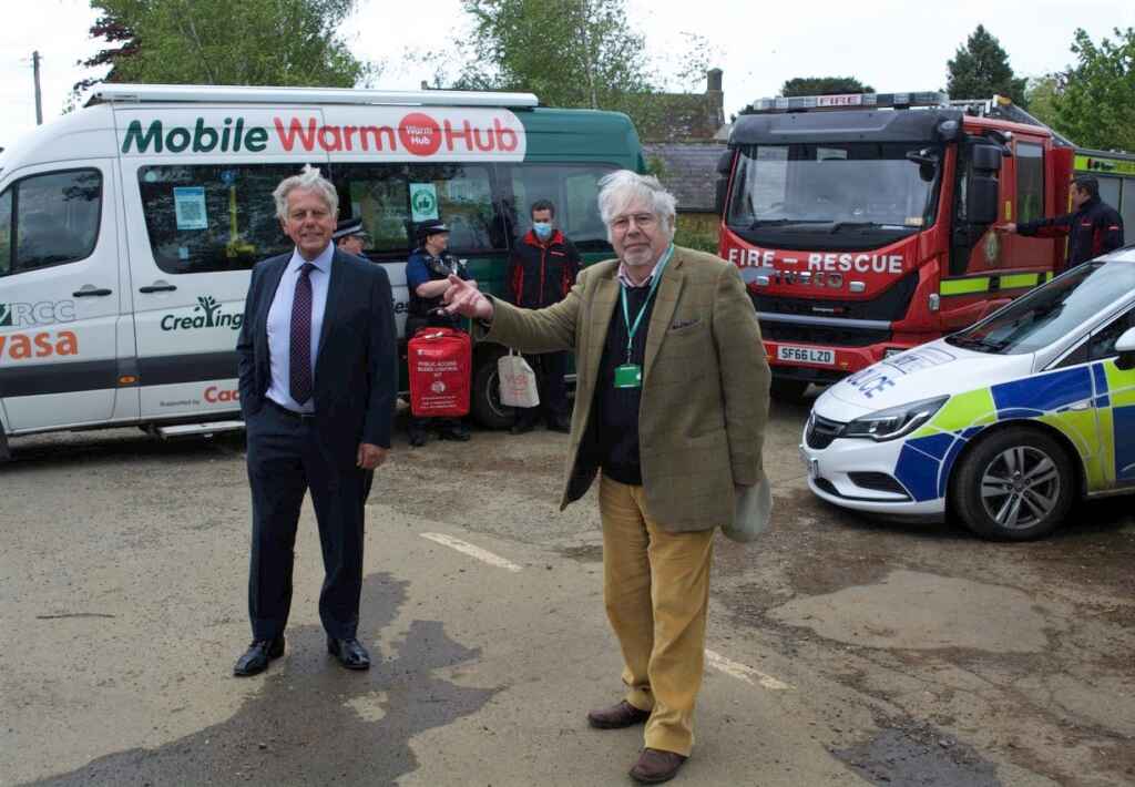 Two men in front of minibus and emergency service vehicles