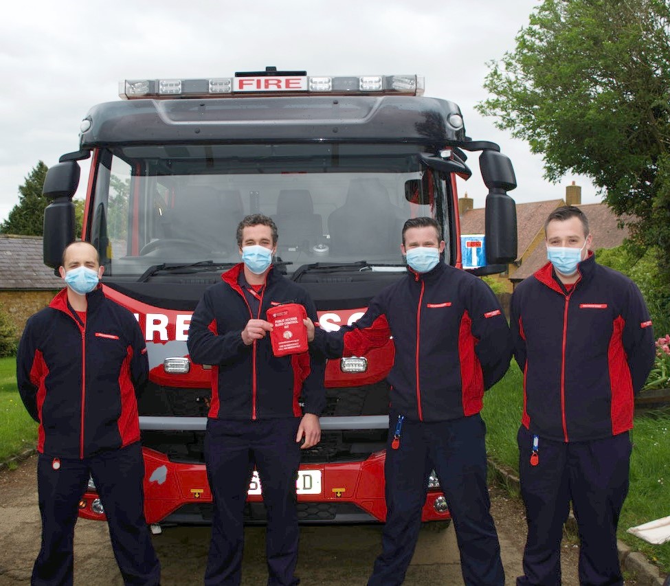 Four fireman in front of a fire engine