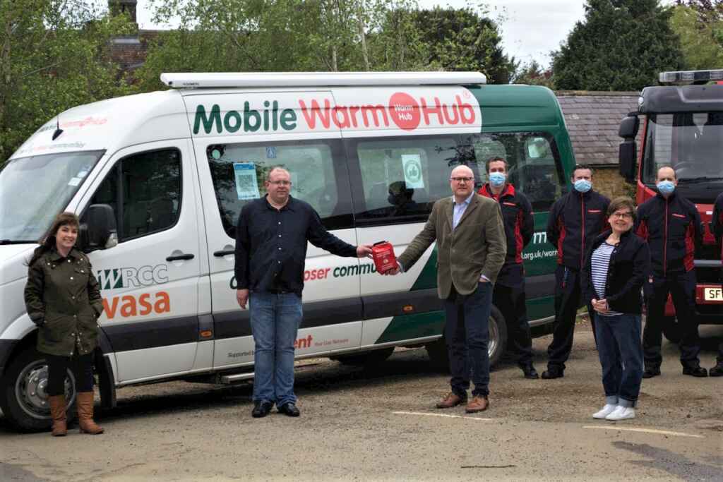 People standing in front of minibus with Mobile Warm Hub lettering and logo