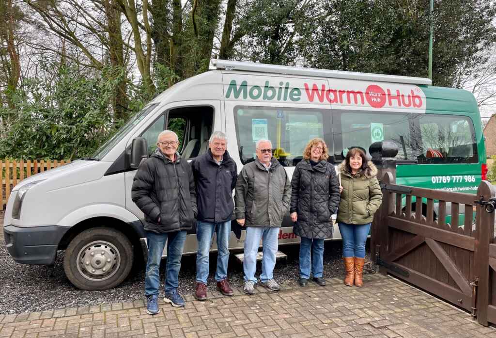 Group of people standing in front of green and white minibus with "Mobile Warm Hub" branding