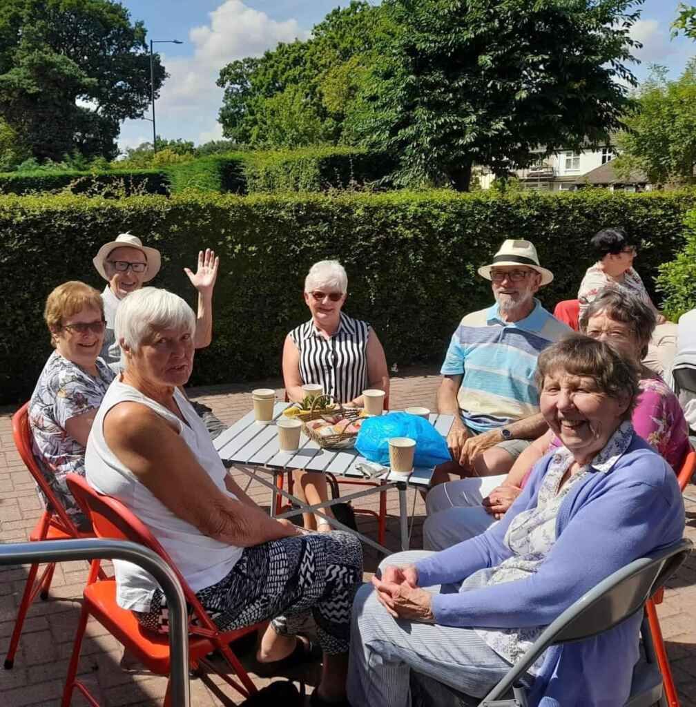 Group of people sitting round a table waving